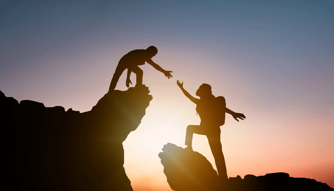person-helping-another-person-on-rocky-mountain